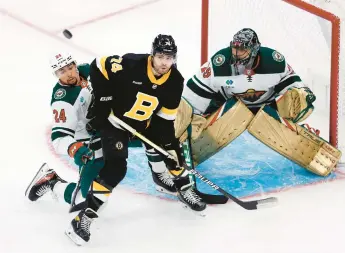  ?? DWYER/AP
MICHAEL ?? The Boston Bruins’ Jake DeBrusk, middle, and the Minnesota Wild’s Matt Dumba, left, battle for the puck in front of Wild goalie Marc-Andre Fleury during the first period on Saturday in Boston. The Bruins remain undefeated at home this season.