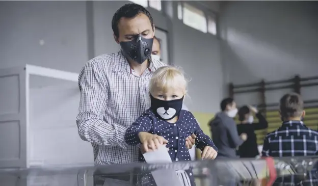  ?? PICTURE: OMAR MARQUES/GETTY IMAGES ?? 0 A man wears a protective face mask and holds a child while casting a vote in Rybnik during Poland’s presidenti­al elections run-off