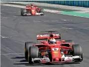  ?? (AFP) ?? Ferrari’s Sebastian Vettel drives over the finish line followed by his teammate Kimi Raikkonen at the Hungarian Grand Prix on Sunday