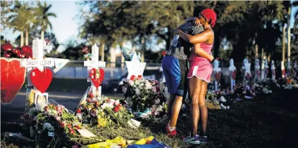  ?? PHOTOS: REUTERS ?? Suffering . . . Adin Chistian (16), a student of the Marjory Stoneman Douglas High School, embraces his mother, Denyse, next to the crosses and Stars of David placed in front of the school to commemorat­e victims of last week’s Florida shooting. Right:...