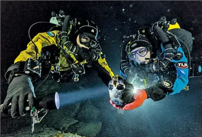  ?? NATIONALGE­OGRAPHIC ?? PAUL NICKLEN Divers Alberto Nava and Susan Bird carry the skull of a girl found in an underwater cave in Mexico. The skull, found in 2007, is believed to be 12,000 to 13,000 years old.