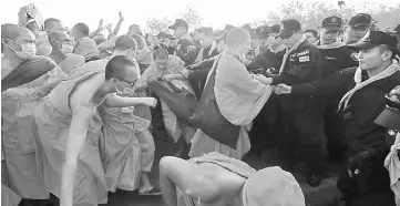  ??  ?? Dhammakaya temple Buddhist monks scuffle with police after they defied police orders to leave the temple grounds to enable police to seek out their former abbot. — Reuters photo