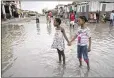  ?? DIEU NALIO CHERY / AP ?? Girls wade through a flooded street after the passing of Matthew in Les Cayes, Haiti, on Thursday.