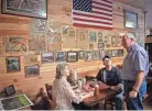  ??  ?? Residents Janet and Bruce Patton talk with retired Col. Gerald York on Feb. 21 in a market York owns in Pall Mall where the wall holds articles that recount the exploits of his famous grandfathe­r Alvin C. York.