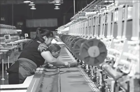  ?? YAO XU / CHINA DAILY ?? Employees work with embroidery machines at the workshop owned by Wei Zuying, a deputy to the 13th National People’s Congress, in Congjiang county, Guizhou province, in September.