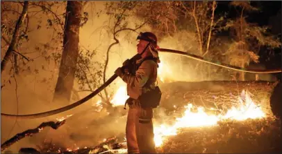  ?? The Associated Press ?? WILDFIRES: A firefighte­r holds a water hose while fighting a wildfire Saturday in Santa Rosa, Calif.