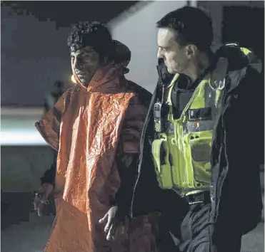  ?? ?? ↑ A man is escorted by Border Force officials after being picked up in the channel on the coast of England