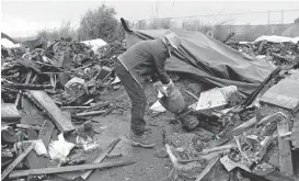  ?? DAN HONDA/STAFF ?? Darold Leite pulls out a burned drum Tuesday that he says belonged to a friend at an area near Oakport Field in Oakland. The debris here is believed to be from the Ghost Ship fire. Leite lived in an area outside and behind the Ghost Ship warehouse and...