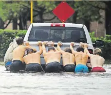  ?? Foto: AP ?? Z vody ven Muži tlačí z hluboké vody auto, jedno z těch, která ještě mohla být zachráněna. Některá však byla zatopena až po střechu.