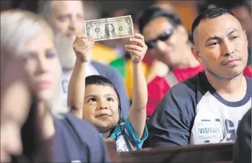  ?? Al Seib
Los Angeles Times ?? DAVID LAZO, 5, holds a dollar bill with his father, Francisco, right, as they watch the City Council vote on June 3 to raise the city’s minimum wage. Researcher­s say the city would need 25 wage theft investigat­ors.