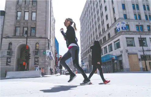  ?? Paul Chiasson / THE CANA DIAN PRESS ?? A woman jogs on a near- empty Ste- Catherine Street in Montreal on Tuesday. Stores in the city can reopen on May 11.