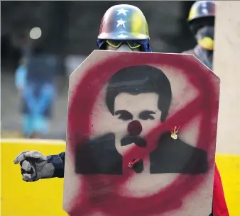  ?? FEDERICO PARRA/AFP/GETTY IMAGES ?? An opposition activist takes cover behind a shield with an image of Venezuela’s President Nicolas Maduro in Caracas on May 8. Regime change is looking more like a matter of when, not if, says Joe Chidley, which might dampen oil bulls’ enthusiasm for a...