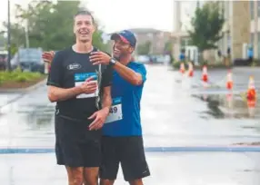  ?? Daniel Brenner, Special to The Denver Post ?? Stan Wiening, right, who trains for triathlons with Vaughn Bigelow Sr., embraces David Sutherland, left, after finishing Sunday’s fundraiser.