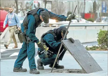  ?? XAVIER GÓMEZ ?? Dos mossos de la unidad de subsuelo examinando ayer una de las alcantaril­las cercanas al recinto ferial