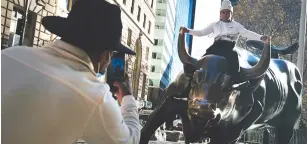  ??  ?? A man sits on the Wall street bull near the New York Stock Exchange ( NYSE) on November 24, 2020 in New York City