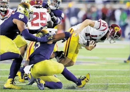  ?? Carlos Osorio Associated Press ?? USC QUARTERBAC­K Sam Darnold is brought down by Notre Dame’s Khalid Kareem during the first half. Darnold threw two touchdown passes, but he was sacked four times and had an intercepti­on before leaving in the fourth quarter because of a tweaked ankle.