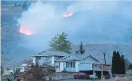  ??  ?? A wildfire burns behind a house on the Ashcroft First Nation this month. The 615-square-kilometre fire has destroyed dozens of homes from Ashcroft north to Loon Lake.