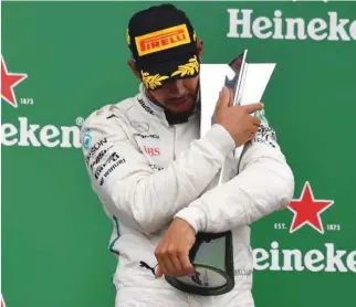  ?? – AFP ?? PRIZED POSSESSION: Mercedes’ British driver Lewis Hamilton celebrates with his trophy on the podium after winning the F1 Brazil Grand Prix at the Interlagos racetrack in Sao Paulo, Brazil.