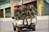  ?? CELLOU BINANI/AFP VIA GETTY IMAGES ?? Members of the Armed Forces of Guinea drive through the central neighborho­od of Kaloum in Conakry on Sunday after sustained gunfire was heard.