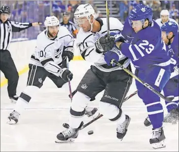  ?? Nathan Denette Associated Press ?? THE KINGS’ Jeff Carter, center, gets tangled up with Toronto’s Travis Dermott during a battle for a loose puck in the third period Monday. The Kings outshot the Maple Leafs 34-25 but managed only one goal.