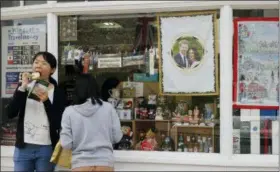  ??  ?? Tourists stand near a shop selling royal memorabili­a near Windsor Castle in Windsor, England, Friday.