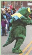  ??  ?? Lola Therrien waves to a parade participan­t dressed as a dinosaur during last year’s MainX24.