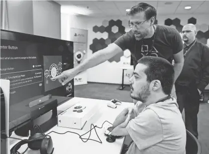  ?? ?? Martin Shane, right, customizes the button layout on the Sony Access controller Sept. 28 before playing a video game at Sony Interactiv­e Entertainm­ent headquarte­rs in San Mateo, Calif.