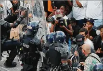  ?? CURTIS COMPTON / CCOMPTON@AJC.COM ?? After she was released from being detained, photojourn­alist Alyssa Pointer (center, in ballcap) was recording police officers kneeling in solidarity with protesters.