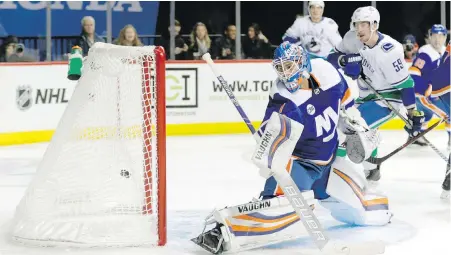  ?? FRANK FRANKLIN II, THE ASSOCIATED PRESS ?? Canucks centre Tim Schaller looks on Tuesday as Islanders goaltender Thomas Greiss reacts too late to a puck shot past him by Vancouver’s Brendan Leipsic during the first period.