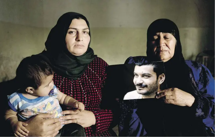  ?? PHOTOS: MAYA ALLERUZZO/THE ASSOCIATED PRESS ?? Hind Zaki, left, the wife of death row prisoner Ismail Saleh, and Saleh’s mother pose with his portrait at their home in Mosul, Iraq. The couple’s daughter Safaa, left, did not get to meet her father before he was sentenced to death by an Iraqi court for his alleged associatio­n with the Islamic State group.