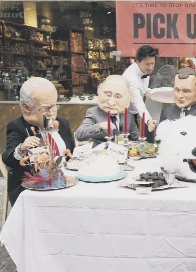  ?? ?? Actors dressed in masks depicting world leaders dine at a banquet of environmen­tal and climate degradatio­n during a performanc­e on Buchanan Street during the COP26 summit