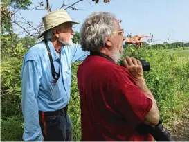  ?? DALE BOWMAN/SUN-TIMES ?? E.J. Neafsey (above, left) and Joel Greenberg interrupt their discussion of Wolf Road Prairie and its plants to find a late-spring bird. At right, a view down one of the nearly 100-year-old sidewalks that remain at Wolf Road Prairie.