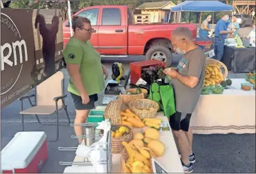  ?? Doug Walker ?? Katie Bridges (left) co-owner of Chewy’s Backyard Farm, helps a customer at the Ridge Ferry Farmers Market. Chewy’s will be accepting SNAP/EBT payments at the market in Ridge Ferry Park the rest of the summer.