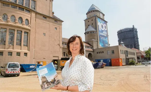  ?? Fotos: Annette Zoepf ?? Planerin Tatjana Kocher von den Stadtwerke­n Augsburg hält eine Broschüre in der Hand, die verdeutlic­ht, dass es jetzt auf dem Gaswerkgel­ände mit den Arbeiten losgeht. Links ist das Ofenhaus, in der Mitte steht der ehemalige Behältertu­rm und rechts ist...