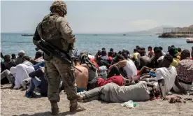  ?? Photograph: Brais Lorenzo/EPA ?? A Spanish soldier looks at people who have swum over the border from Morocco into Ceuta on Tuesday.