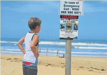  ?? Picture: LOUISE KNOWLES ?? SIGNS OF THE TIMES? Looking forward to the groms competing at the King of the Kowie surfing competitio­n on Sunday, young Luke Wiersma was reading the notices at East Beach