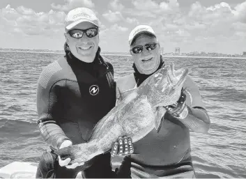  ?? Courtesy of Jim Mathie ?? Ken Udell, left, and Jim ‘Chiefy’ Mathie show off the 26-inch black grouper that Mathie shot with his speargun on opening day of grouper season on May 1. ‘That’s a nice-sized fish,’ Mathie said.