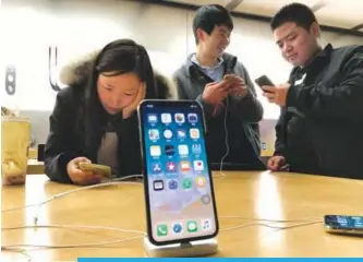  ??  ?? BEIJING: In this file photo, shoppers check out the iPhone X at an Apple store in Beijing, China. —AP