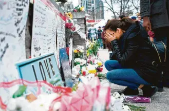  ?? Nathan Denette / The Canadian Press via Associated Press ?? A woman fights back tears at a memorial along Yonge Street in Toronto on Tuesday, the day after a driver drove a van down sidewalks, striking and killing numerous pedestrian­s in his path.