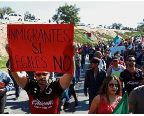  ?? — Reuters ?? Firm stance: A demonstrat­or holding a placard that reads ‘Immigrants yes, illegals no’ during a protest in Tijuana.