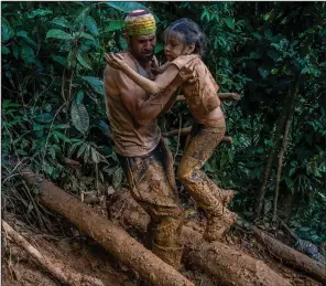  ?? (The New York Times/Federico Rios) ?? Angel Garcia helps Sarah Cuauro trudge up the Hill of Death in the Darien Gap between Colombia and Panama on Oct. 6, 2022.