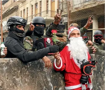  ?? AP ?? Iraqi security forces take photos with a demonstrat­or dressed as Santa Claus during a protest in Rasheed St, Baghdad yesterday.