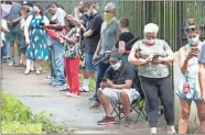  ?? AP-John Bazemore ?? Steven Posey checks his phone as he waits to vote, Tuesday at Central Park in Atlanta. Voters reported wait times of three hours.