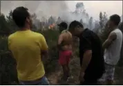  ?? PAULO DUARTE — THE ASSOCIATED PRESS ?? People watch Portuguese firefighte­rs working to stop a forest fire from reaching the village of Figueiro dos Vinhos in central Portugal, Sunday. Portugal’s president says the country’s pain “knows no end” as it mourns at least 62 people killed in the...