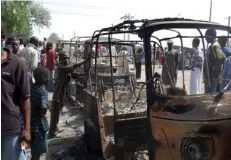  ??  ?? RESIDENTS SURVEY vehicles damaged after a bomb blast at an elementary school in Maiduguri, Nigeria, on February 29.