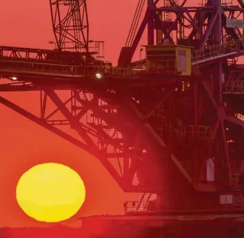  ?? Foto: Patrick Pleul, dpa ?? Farbenpräc­htig leuchtet der Sonnenaufg­ang am Rande des Braunkohle­tagebaus der Lausitz Energie Bergbau AG. Doch der Blick auf die Klimabilan­z von Kohle ist eher düster.