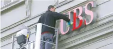  ?? — AFP ?? A man cleans the logo of Swiss bank UBS on a branch in Bern, Switzerlan­d.