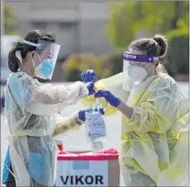  ?? Ellen Schmidt Las Vegas Review-journal file ?? Volunteers place a nasal swab into a container May 9 at the COVID-19 drive-thru testing site at Calvary Chapel Las Vegas.