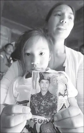  ?? ANDY ZAPATA ?? Kiesh Darriel holds a photograph of her father, PO3 Daniel Tegwa as her mother Robelyn recounts her last communicat­ion with her husband at their home in Baguio City yesterday.