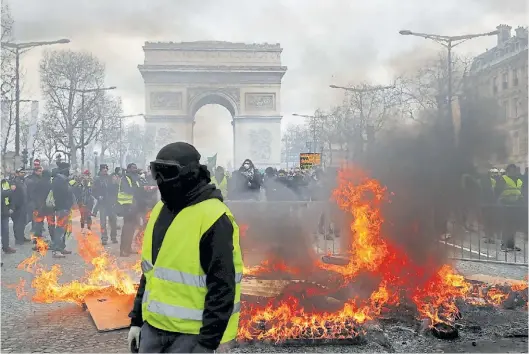  ?? AP ?? Humo. Un grupo de “chalecos amarillos” protesta frente al Arco del Triunfo, durante una de las marchas contra Macron en marzo.